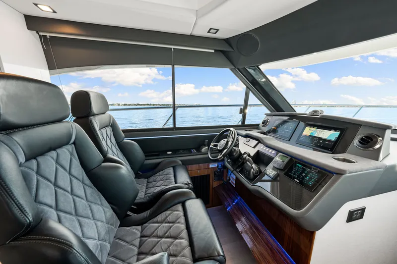 Slide: The Image of 2024 Riviera 4600 Sport Yacht Platinum Edition helm with luxurious leather seating and advanced navigation displays. - 53