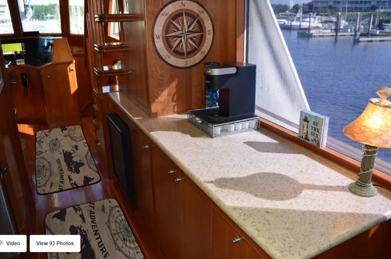 Slide: The Image of 2002 Grand Alaskan Cockpit Motor Yacht interior with compass decor and marina view. - 20