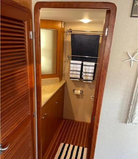 Slide: The Image of 2002 Grand Alaskan Cockpit Motor Yacht bathroom with wooden cabinetry and striped rug. - 37