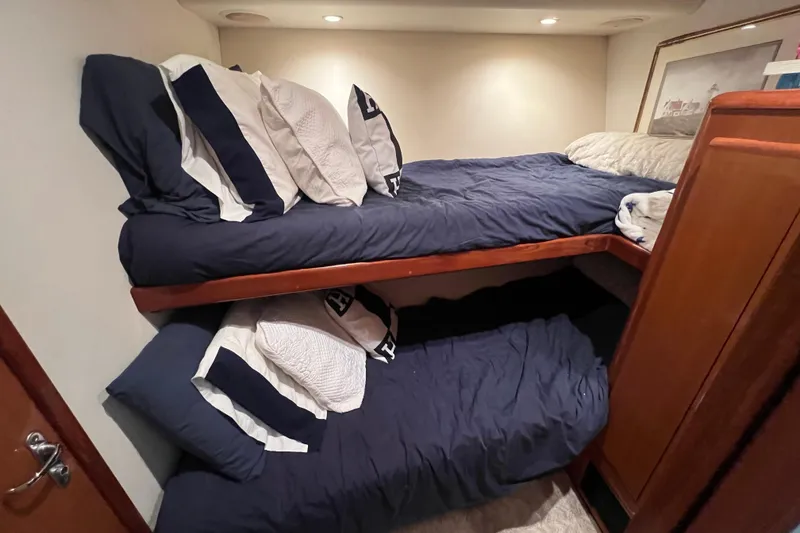 Slide: The Image of Bunk beds in a 1999 Viking 60 CPMY yacht cabin with navy bedding and pillows. - 78