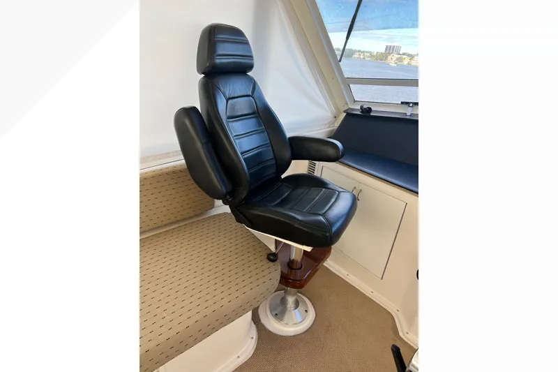 Slide: The Image of Captain's chair in 1999 Viking 60 CPMY yacht cockpit, featuring black leather upholstery. - 52