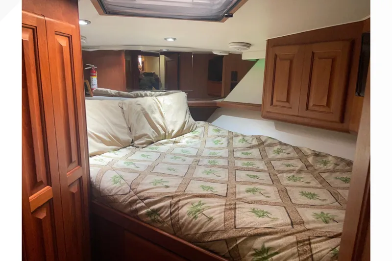 Slide: The Image of Cozy bedroom in 1991 Viking Convertible yacht with wood cabinets and patterned bedding. - 57