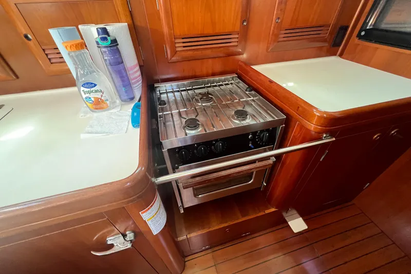 Slide: The Image of Galley kitchen in 2001 Beneteau Oceanis 473 yacht with stove and wooden cabinetry. - 71