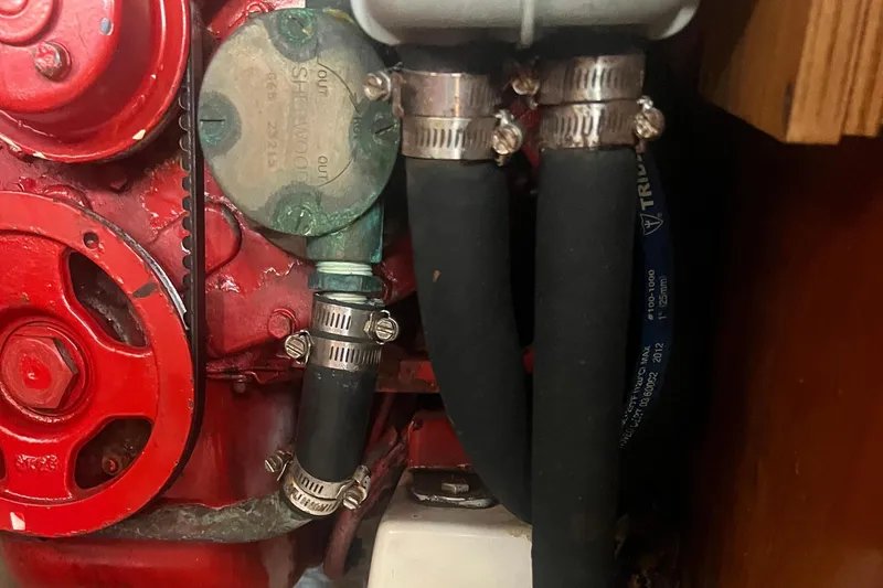 Slide: The Image of Engine compartment of a 2001 Beneteau Oceanis 473 sailboat, showing hoses and mechanical components. - 107