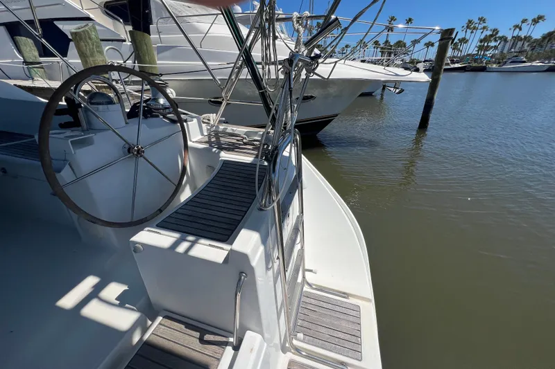 Slide: The Image of Sailboat deck view of 2001 Beneteau Oceanis 473, featuring steering wheel and marina backdrop. - 45