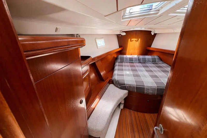 Slide: The Image of Cozy cabin interior of 2001 Beneteau 473 sailboat with wooden finish and plaid bedding. - 88