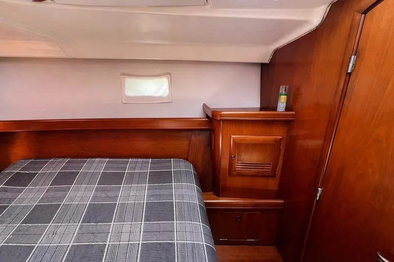 Slide: The Image of Cozy cabin interior of 2001 Beneteau 473 yacht with wood paneling and plaid bedding. - 91