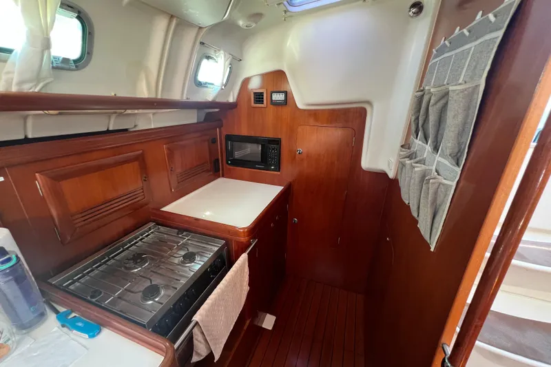 Slide: The Image of Cozy kitchen area in a 2001 Beneteau Oceanis 473 sailboat with wood cabinetry and appliances. - 69