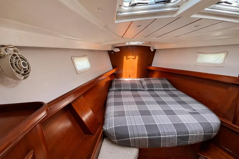 Slide: The Image of Cozy cabin interior of 2001 Beneteau 473 sailboat with plaid bedding and wooden finish. - 89