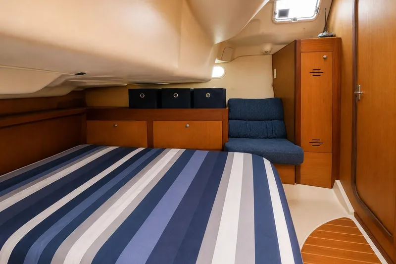 Slide: The Image of Cozy cabin interior of 1999 Hunter 380 sailboat with striped bedding and wooden storage. - 67
