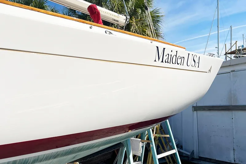 Slide: The Image of 2019 Alerion Express 20 sailboat named "Maiden USA" on a stand, palm trees in background. - 2
