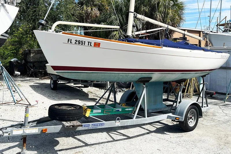 Slide: The Image of 2019 Alerion Express 20 sailboat on trailer, parked outdoors with trees in background. - 1