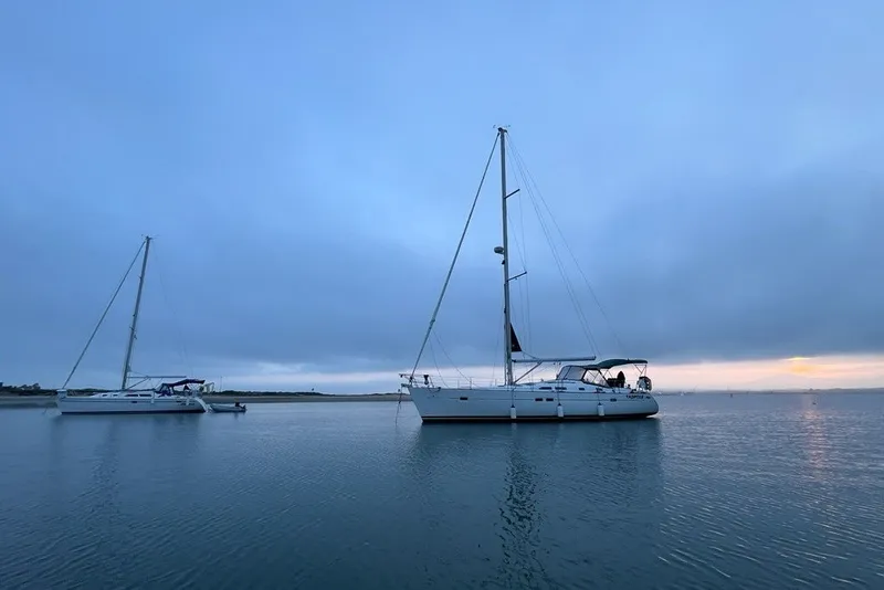 Slide: The Image of 2005 Beneteau Oceanis 423 sailboat anchored on calm water at sunset. - 78