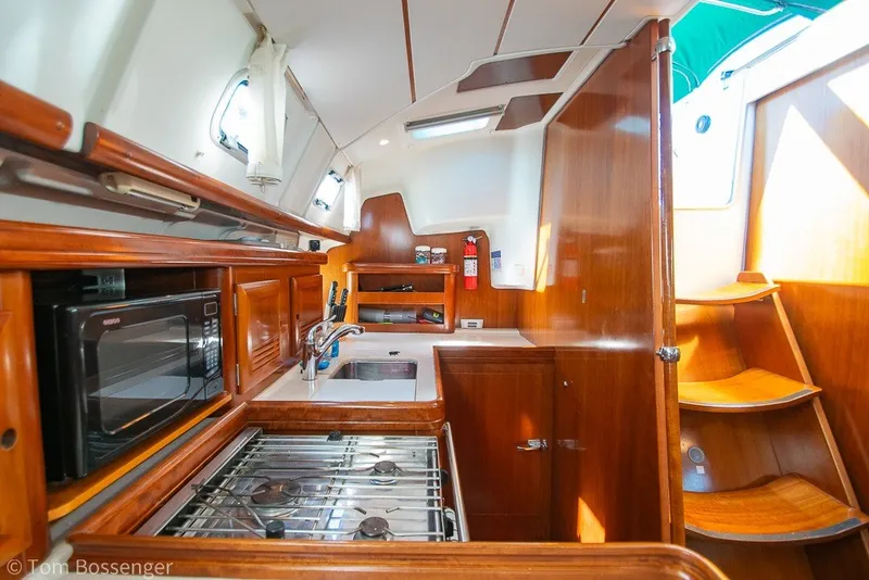 Slide: The Image of Interior of 2005 Beneteau Oceanis 423 yacht, featuring a well-equipped wooden kitchen. - 14