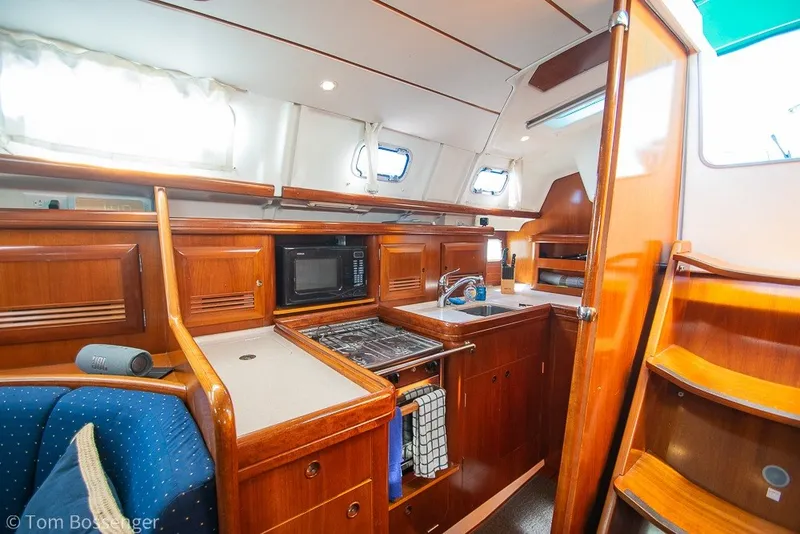 Slide: The Image of Interior of 2005 Beneteau Oceanis 423 yacht, featuring a well-equipped kitchen and wooden cabinetry. - 13