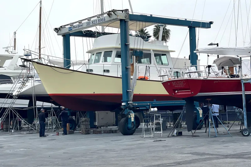Slide: The Image of 1978 Thompson motor yacht in dry dock, undergoing maintenance with nearby red sailboat. - 35
