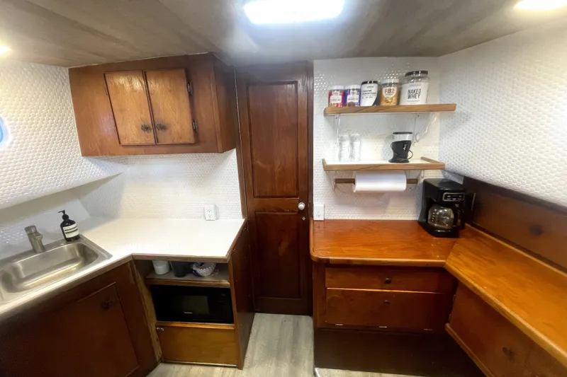 Slide: The Image of 1978 Thompson motor yacht kitchen with wooden cabinets, countertop, sink, and coffee maker. - 13