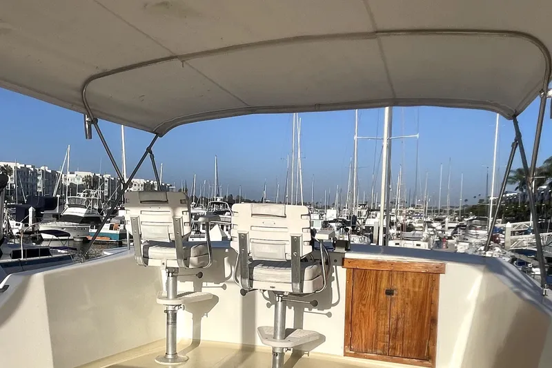 Slide: The Image of 1978 Thompson motor yacht helm with two chairs, marina view, under canopy. - 4