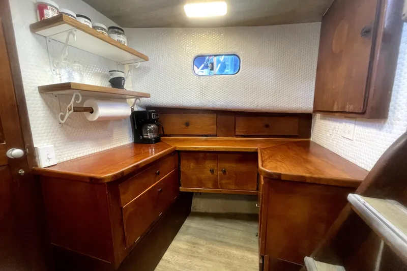 Slide: The Image of 1978 Thompson motor yacht interior with wooden cabinetry and shelves, featuring a coffee maker. - 12