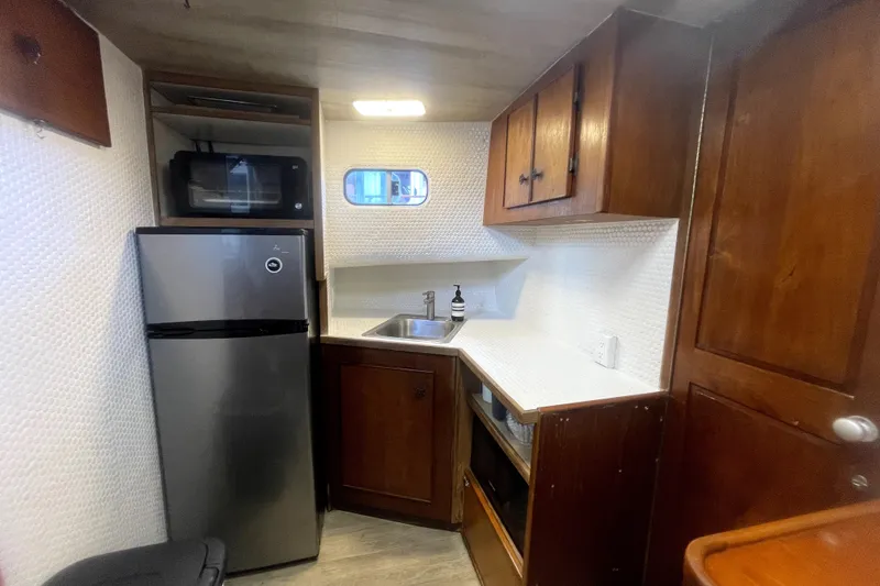 Slide: The Image of 1978 Thompson motor yacht kitchen with fridge, microwave, sink, and wooden cabinets. - 15