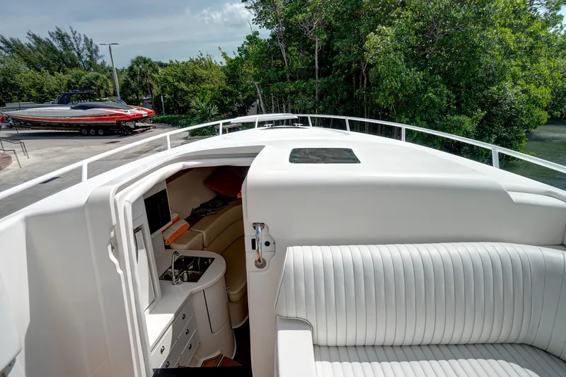Slide: The Image of 2008 Intrepid 370 Cuddy boat interior with seating and kitchenette, docked near lush greenery. - 23