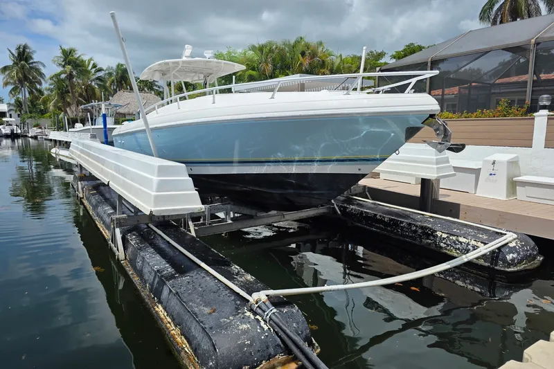 Slide: The Image of 2008 Intrepid 370 Cuddy boat on a lift, docked near palm trees and waterfront homes. - 1