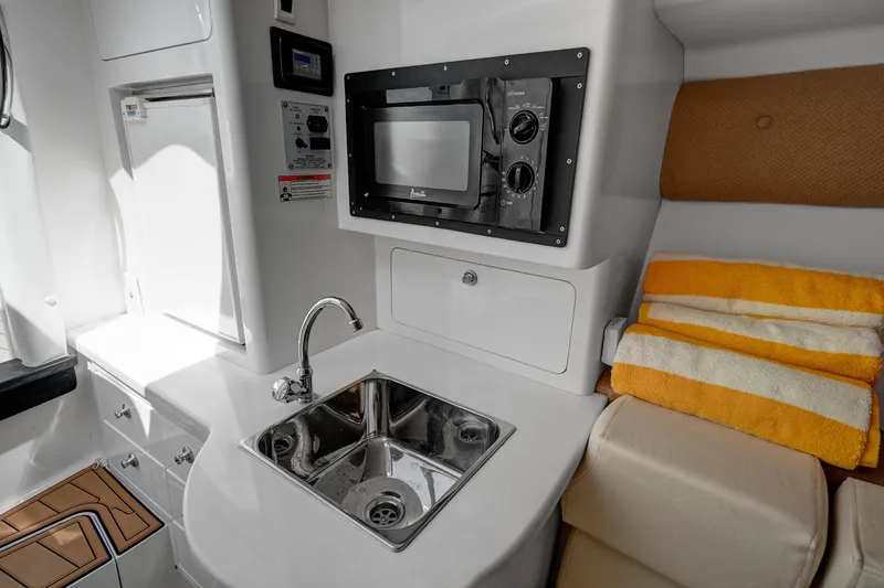 Slide: The Image of Compact kitchen area in a 2008 Intrepid 370 Cuddy boat with sink, microwave, and towels. - 20