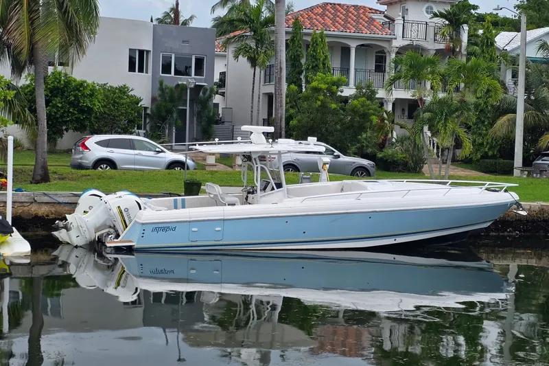 The Image of 2008 Intrepid 370 Cuddy boat docked by waterfront homes, reflecting on calm water. - 0