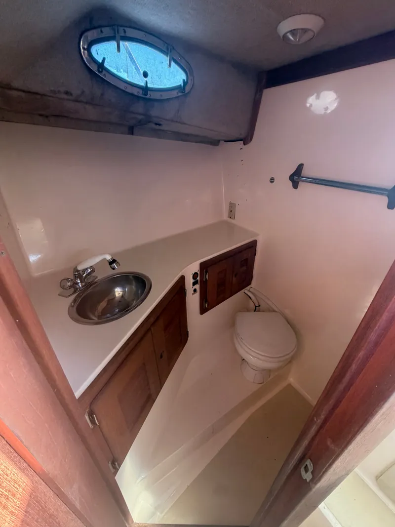 Slide: The Image of The image shows a small boat bathroom with a sink, toilet, and wooden cabinets. - 20