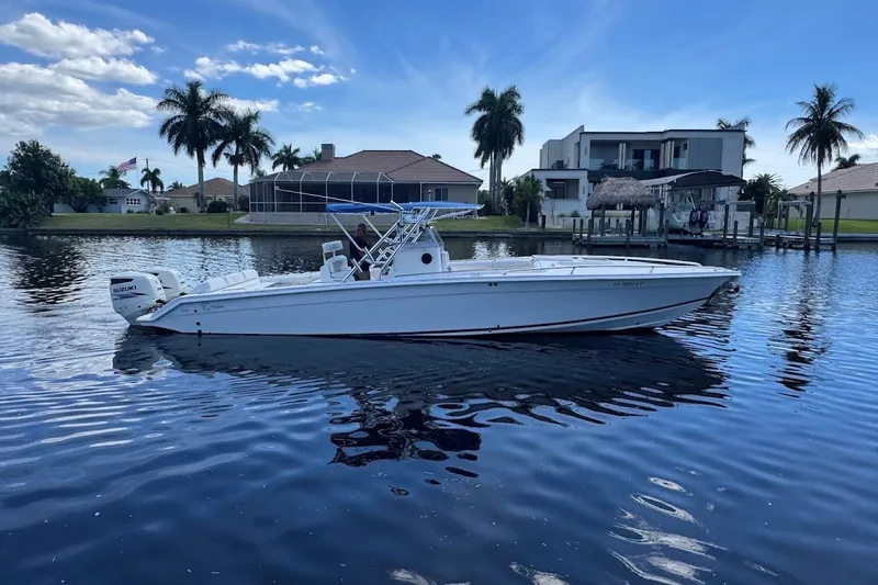 The Image of 2003 Marlago 35 FS boat cruising on a calm waterfront with palm trees and houses. - 0