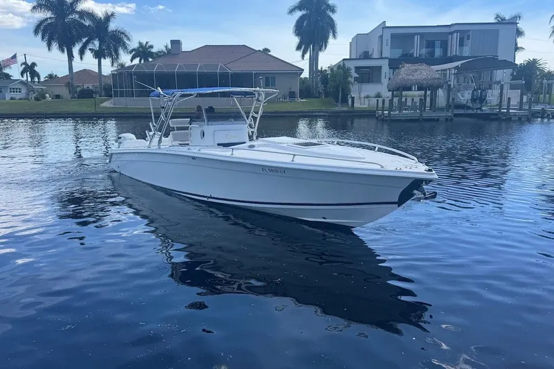 Slide: The Image of 2003 Marlago 35 FS boat on calm water near waterfront homes and palm trees. - 3