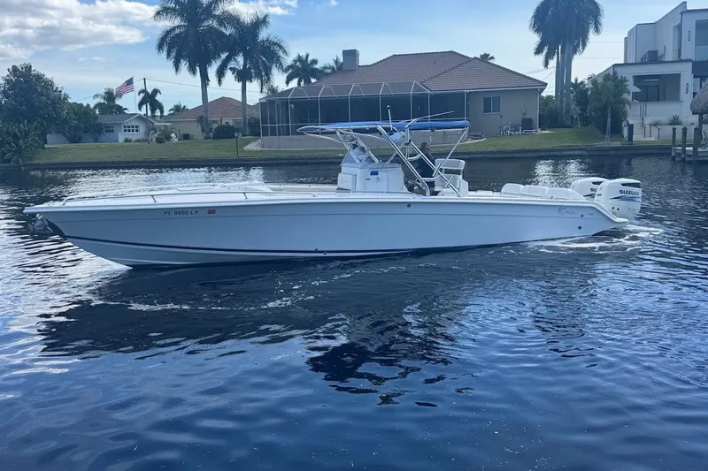 Slide: The Image of 2003 Marlago 35 FS boat cruising on a calm waterway, surrounded by waterfront homes and palm trees. - 7