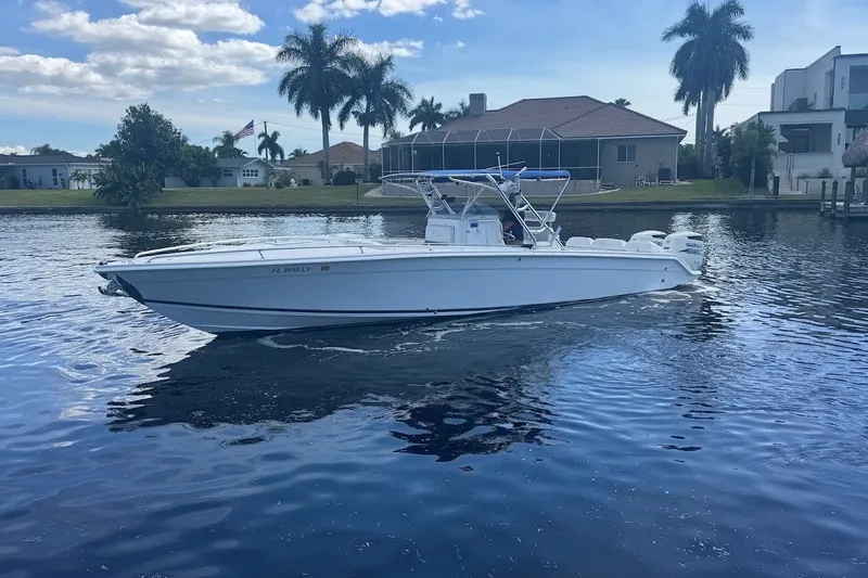 Slide: The Image of 2003 Marlago 35 FS boat on calm water, with houses and palm trees in the background. - 6