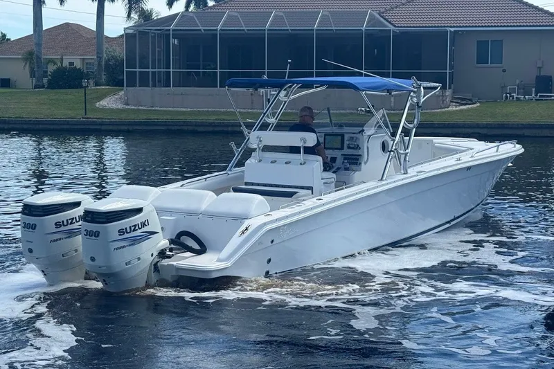 Slide: The Image of 2003 Marlago 35 FS boat with twin Suzuki 300 engines cruising on a calm waterway. - 12