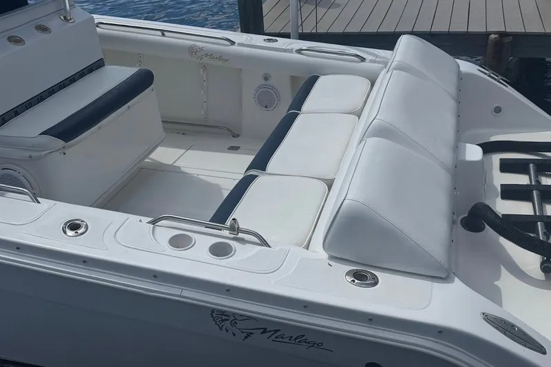 Slide: The Image of 2003 Marlago 35 FS boat interior with white seating and cup holders by the dock. - 15