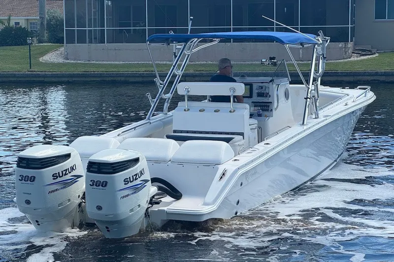 Slide: The Image of 2003 Marlago 35 FS boat with twin Suzuki 300 engines on a calm waterway. - 11