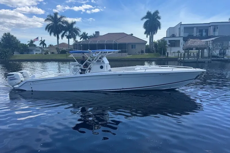 Slide: The Image of 2003 Marlago 35 FS boat on a calm waterway, with palm trees and houses in the background. - 1