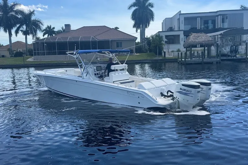 Slide: The Image of 2003 Marlago 35 FS boat cruising on a calm waterway with palm trees in the background. - 9