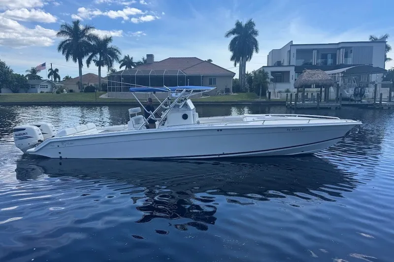 Slide: The Image of 2003 Marlago 35 FS boat on calm water, with waterfront homes and palm trees in the background. - 2