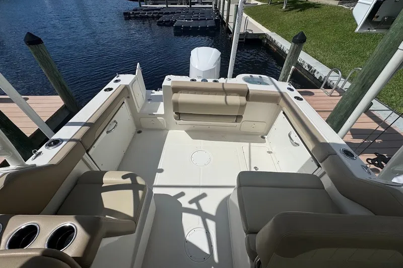 Slide: The Image of 2020 Sailfish 245 DC boat interior with beige seating, docked by the water. - 22