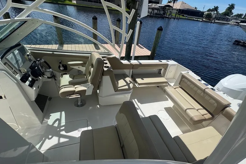 Slide: The Image of 2020 Sailfish 245 DC boat interior with beige seating and steering console by the water. - 25