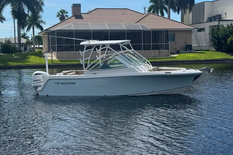 The Image of 2020 Sailfish 245 DC boat on water near a house with palm trees. - 0
