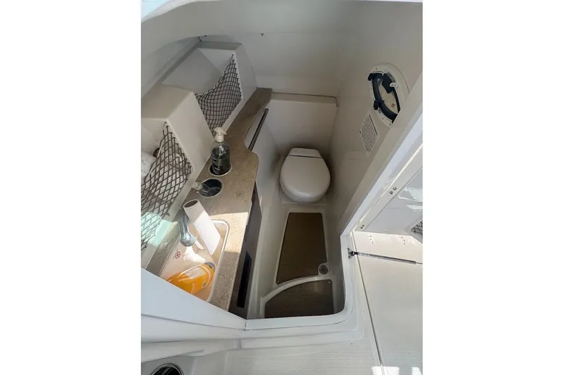 Slide: The Image of 2020 Sailfish 245 DC boat interior with compact bathroom, featuring a toilet and sink. - 21