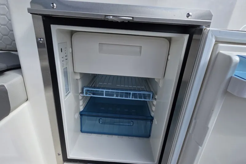 Slide: The Image of Open refrigerator on 2020 Sea Ray SDX 290 boat, showing interior shelves and compartments. - 18