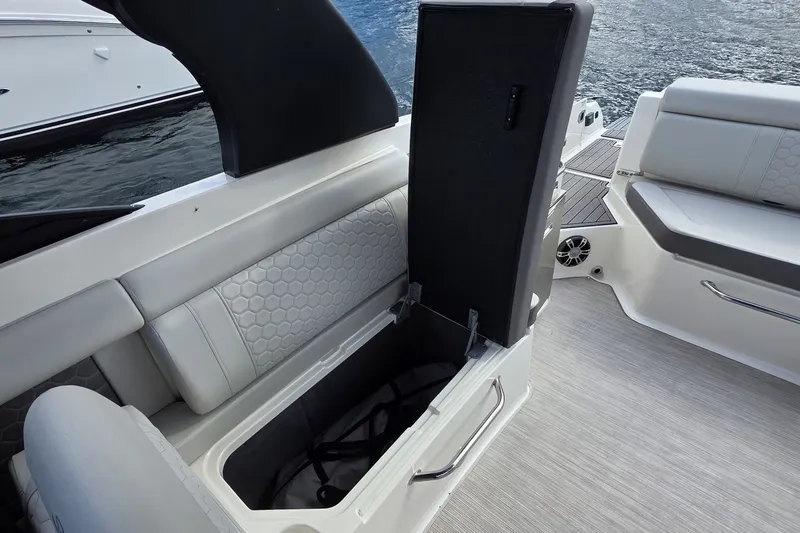 Slide: The Image of 2020 Sea Ray SDX 290 boat with open storage compartment and cushioned seating. - 14