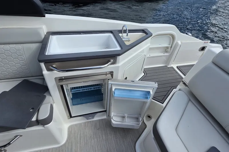 Slide: The Image of 2020 Sea Ray SDX 290 boat interior with sink and open mini-fridge by the water. - 13