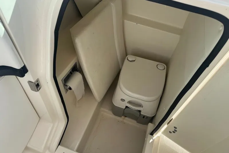 Slide: The Image of 2014 Sea Ray SLX 250 boat interior with compact marine toilet and toilet paper holder. - 13