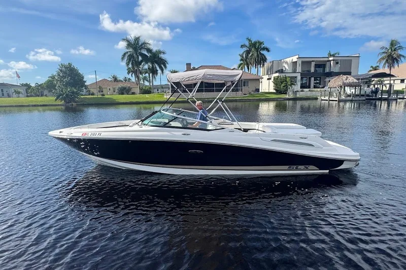 The Image of 2014 Sea Ray SLX 250 boat cruising on a sunny day, surrounded by waterfront homes. - 0