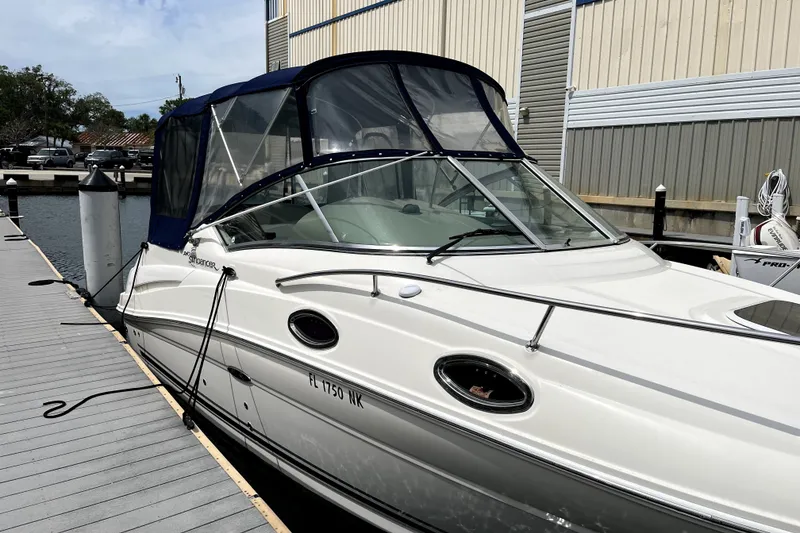 Slide: The Image of 2007 Sea Ray 240 Sundancer docked at marina, featuring sleek design and blue canopy. - 2