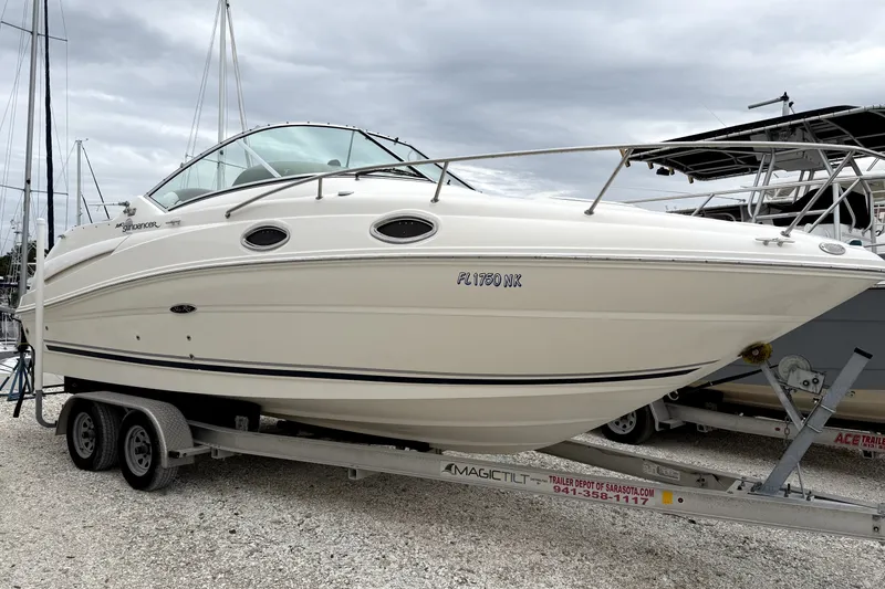 Slide: The Image of 2007 Sea Ray 240 Sundancer boat on trailer, parked outdoors under cloudy sky. - 0